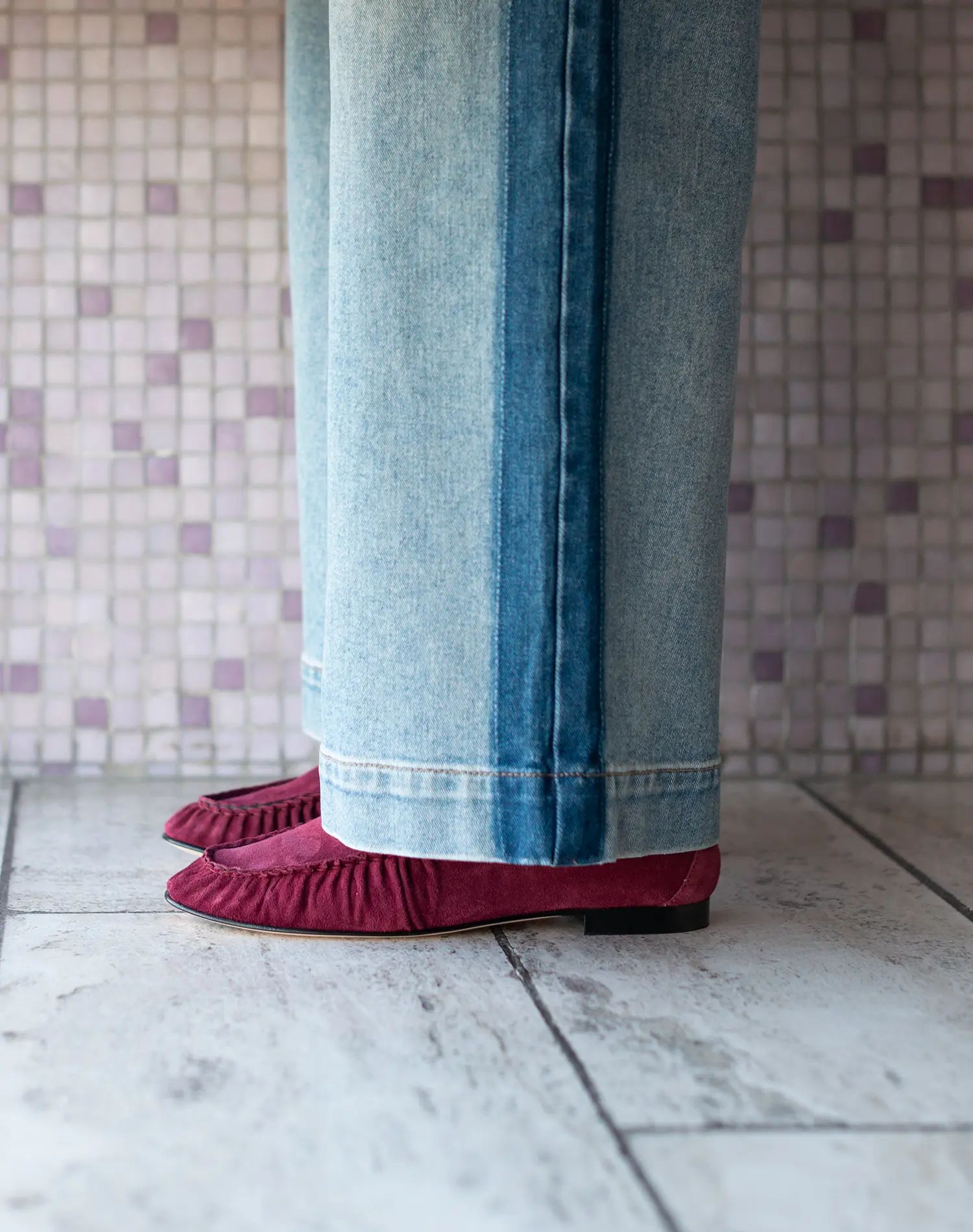 Roze loafers onder jeans op tegelvloer