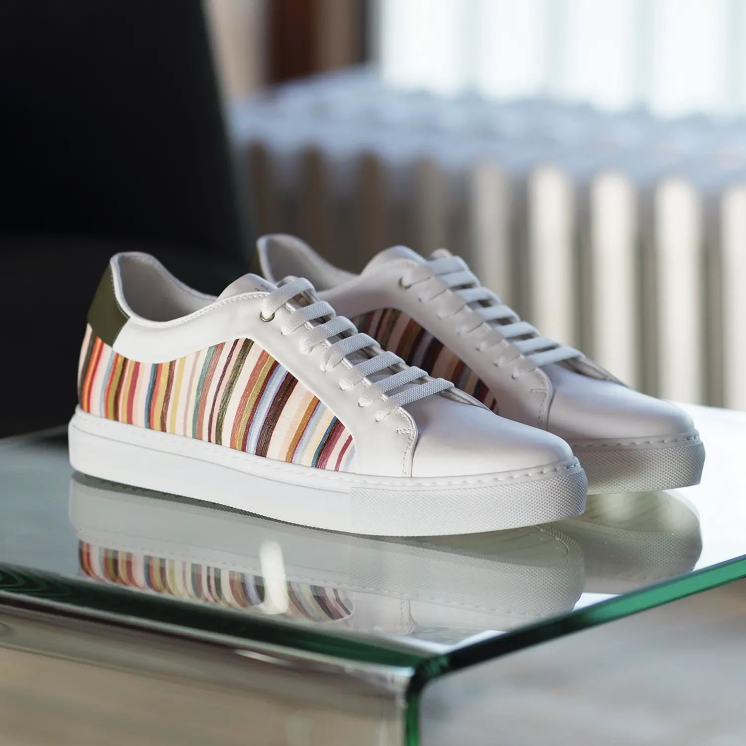 Witte sneakers met kleurrijke strepen op glasplaat