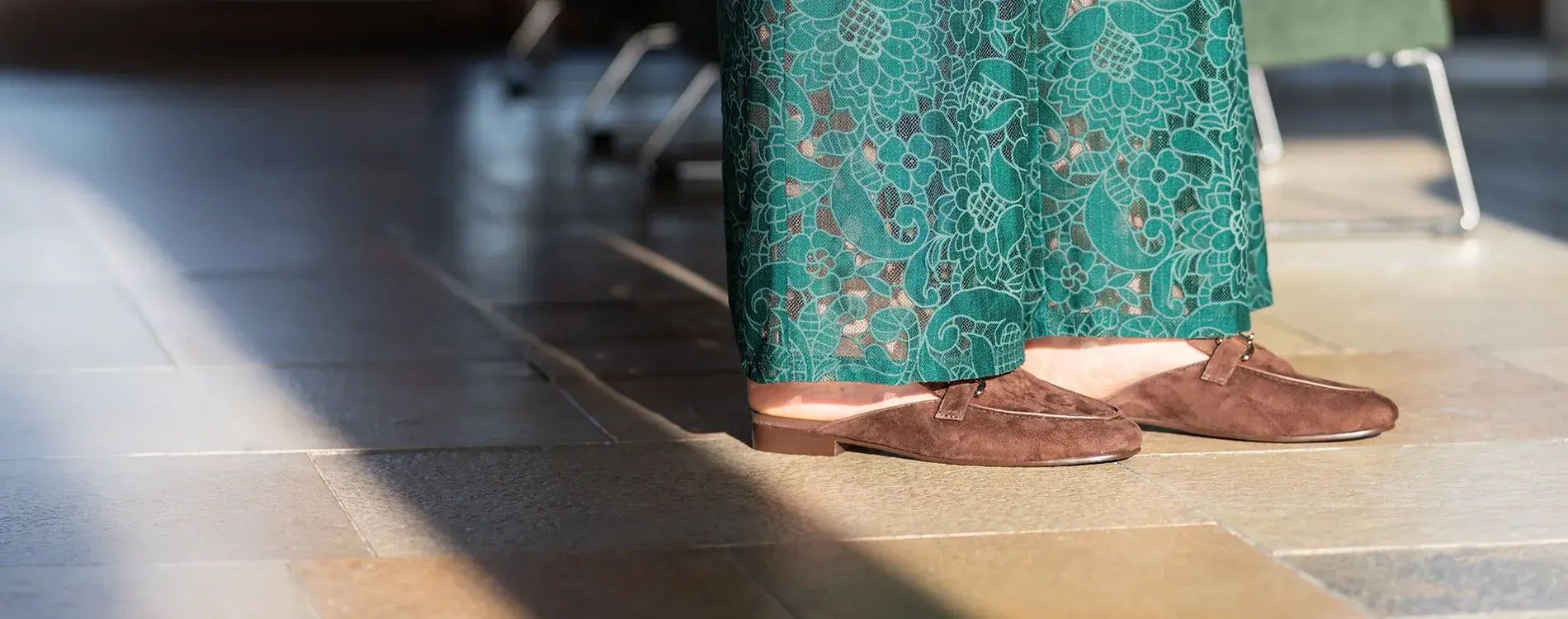 Groene broek met sandalen op tegelvloer in zonlicht